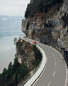 红色汽车摄影照片_在瑞士阿尔卑斯山的特拉肯附近山路上的红色汽车