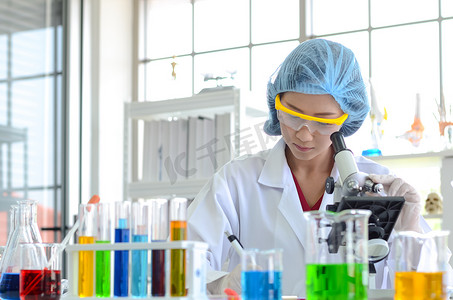 实验室里的女科学家用显微镜做实验。医疗保健技术与药物研发的摄影理念.