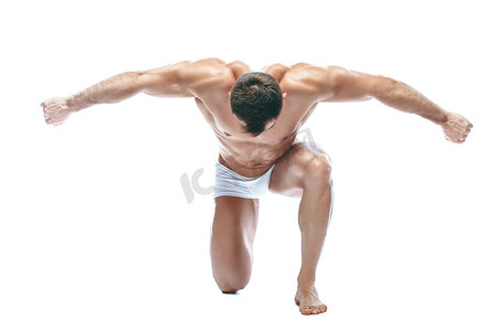 男性男摄影照片_健美的姿势。漂亮的运动男男性力量。健身肌肉世上白色内衣。在孤立的白色背景上。跪