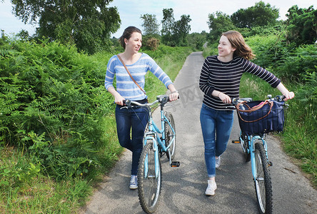 两个年轻人推着自行车沿着乡间小路聊天