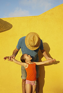 黄墙摄影照片_父亲牵着女儿的胳膊隔着黄墙