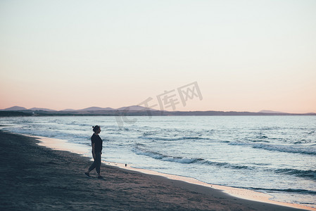 意大利萨萨里索尔索黄昏时分在海滩上散步的女子