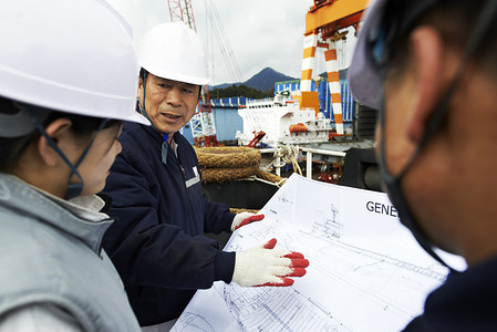 工人在韩国高胜郡造船厂查看平面图