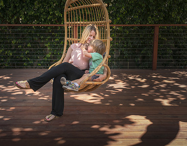 孕妇和儿子在花园的秋千椅上放松