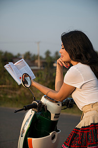骑着轻便摩托车看书的女人
