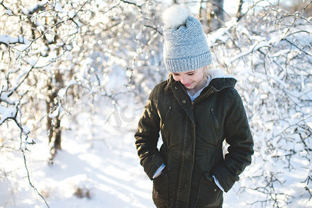 雪景中的年轻女孩双手插在口袋里低头看着