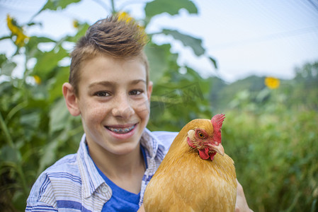 传统花纹摄影照片_田野里抱着母鸡的男孩的肖像