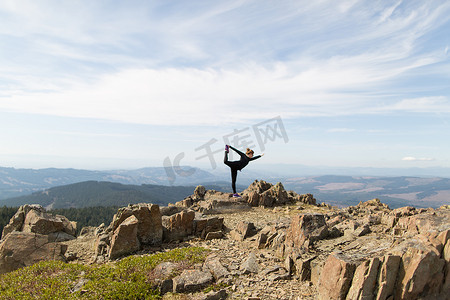 参差不齐摄影照片_美国华盛顿州银星山年轻女子站在岩石上做瑜伽姿势