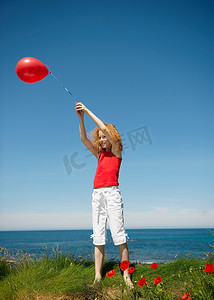拿着红色气球站着的年轻女孩