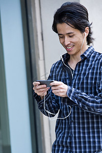 一名中年男子走在城市街道上用智能手机挑选音乐