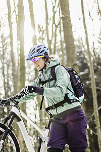 中年女性山地自行车推着自行车穿过森林