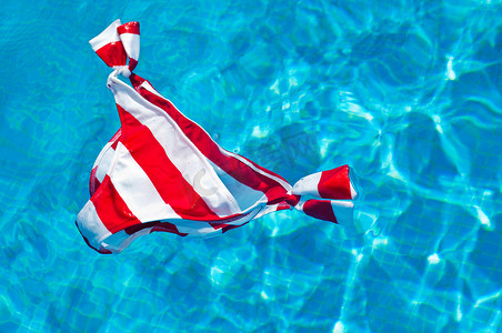 红蓝白摄影照片_漂浮在水面上的红白条纹比基尼底裤