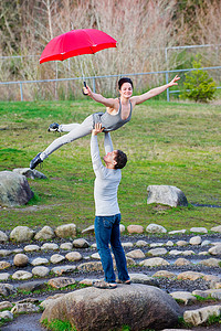 中年舞者打着红伞在石圈里表演