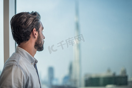 阿联酋迪拜一名商人凝视着窗外的城市景色
