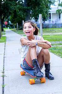 小路上坐在滑板上的女孩肖像