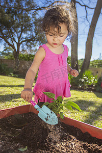 小女孩在花园里在盆子里种植植物拿着铲子
