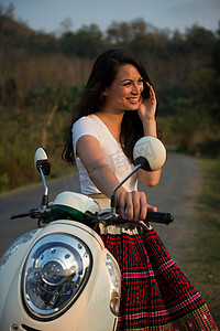 一名女子靠在手机上骑着轻便摩托车