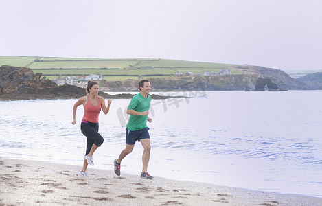 一对情侣在英国德文郡瑟尔斯通的海滩上跑步