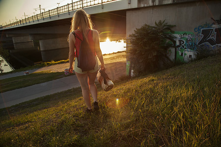 年轻女子在桥和河边散步的后视线