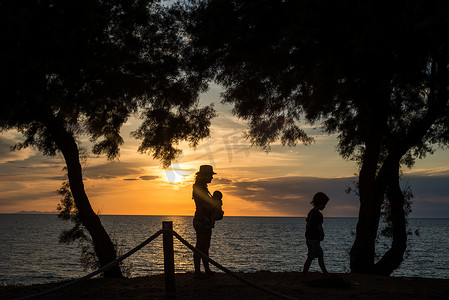 日落时母亲和孩子在水边的剪影意大利