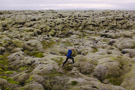 中年妇女行走在起伏的火山景观上的侧视冰岛
