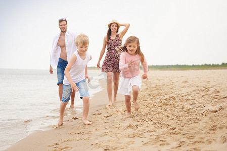 沙滩上的孩子摄影照片_沿着沙滩奔跑的一家人