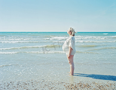孕妇户外摄影照片_站在海滩上的孕妇