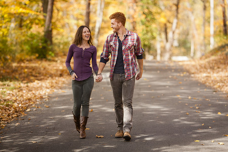 浪漫的年轻情侣在秋林中漫步