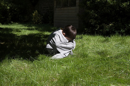 伊甸园摄影照片_蜷缩在花园里的男孩