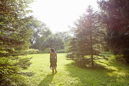 漫步摄影照片_阳光明媚的公园里散步的女人的后视线