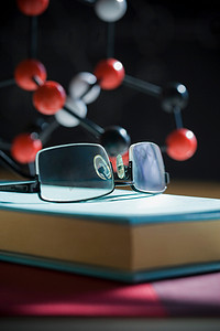 物理教学摄影照片_背景中带有分子模型的眼镜和书籍