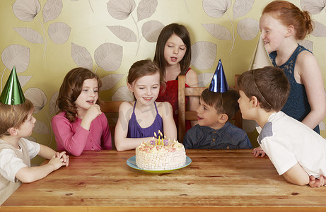 会议桌摄影照片_孩子们在生日聚会上女孩带着蛋糕