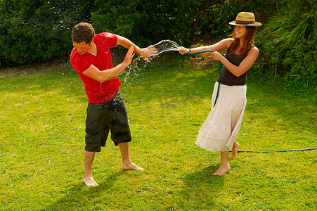 女人用花园软管向男人喷洒