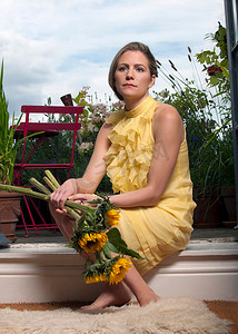 鲜花模特摄影照片_阳台上拿着向日葵的女人
