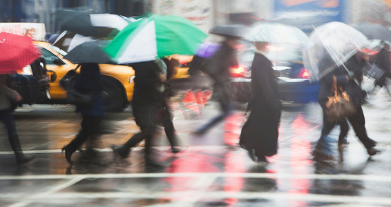 排队的人在雨中穿过城市街道