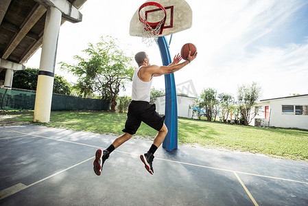 篮球场上年轻人在半空中抱着篮球跳圈的侧视
