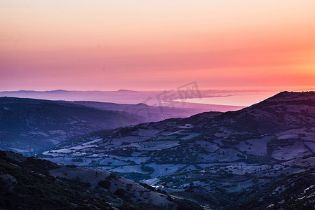 落日流水摄影照片_意大利撒丁岛卡斯特尔萨多橙色的落日海洋和崎岖的山地农田