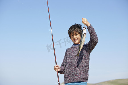 小男孩举着钓鱼竿和鱼