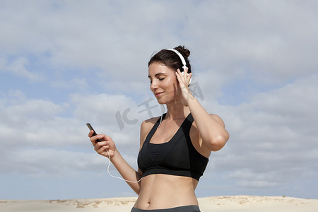 中年女性在海滩锻炼时选择耳机音乐