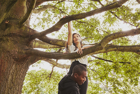 私人教练抬着女人爬上公园的树