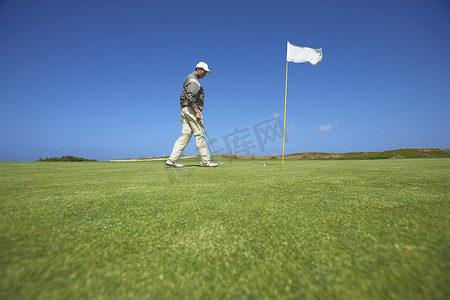 高尔夫球手走向高尔夫球旗俯视的低角度全身侧视图