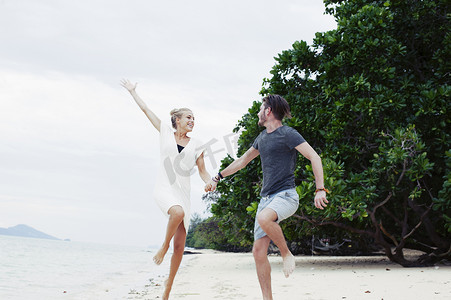 泰国克拉丹一对年轻夫妇在海滩上蹦蹦跳跳嬉戏嬉戏