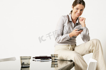 科技空间摄影照片_年轻的女商人坐在办公桌上发短信
