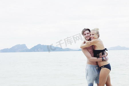 年轻夫妇在海滩上拥抱泰国克拉丹