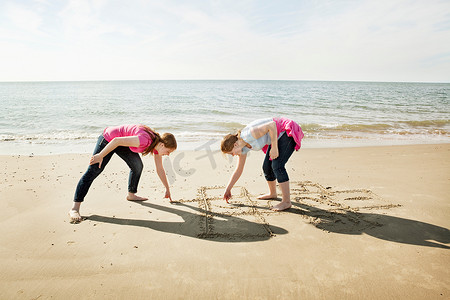 女孩们在沙滩上画跳房子