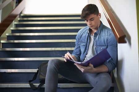 年轻的男大学生坐在楼梯上复习档案