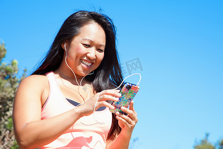 中年女性穿着运动服戴着耳机拿着智能手机