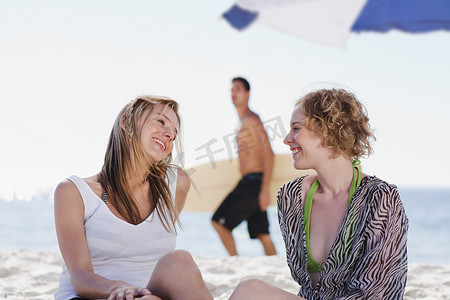 人群交谈摄影照片_微笑的女人在海滩上交谈