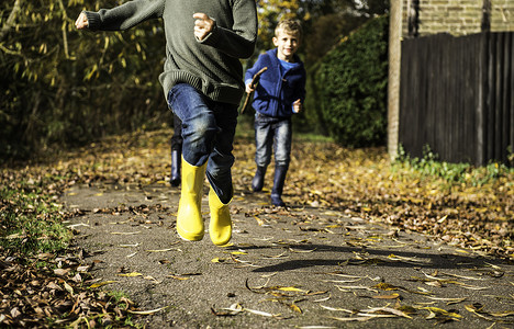 三个男孩沿着秋天的小路奔跑低矮的路段