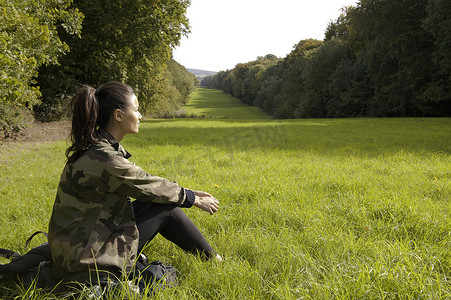 坐在田野里看风景的年轻女子英国白金汉郡大米森登